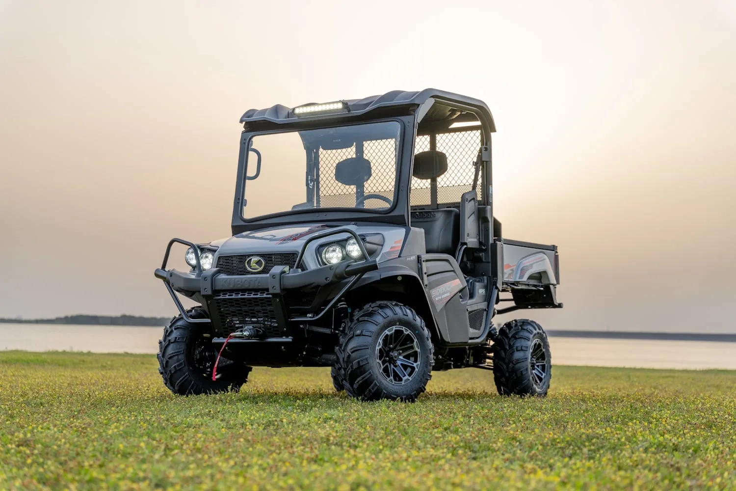 Kubota SIDEKICK RTV-XG850 gas utility vehicle parked on lakeside grass at dusk