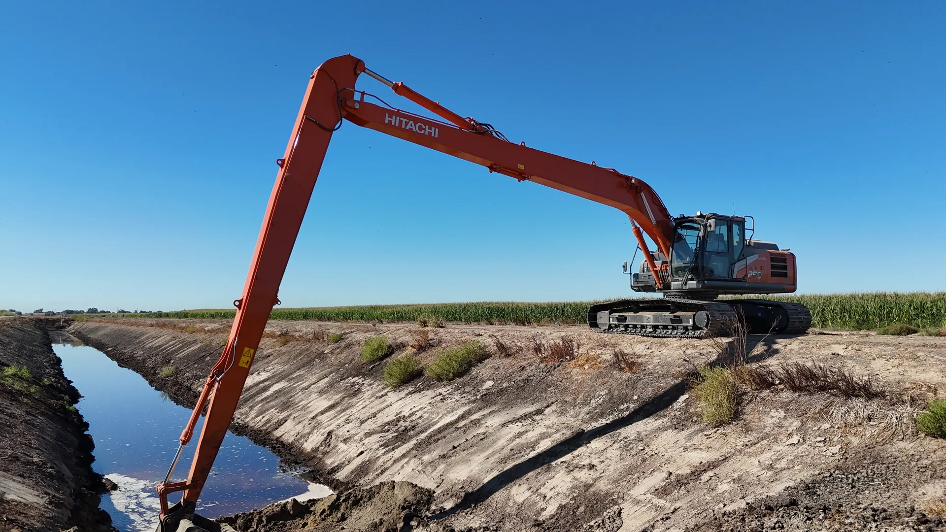 Long-reach Hitachi excavator working beside a canal
