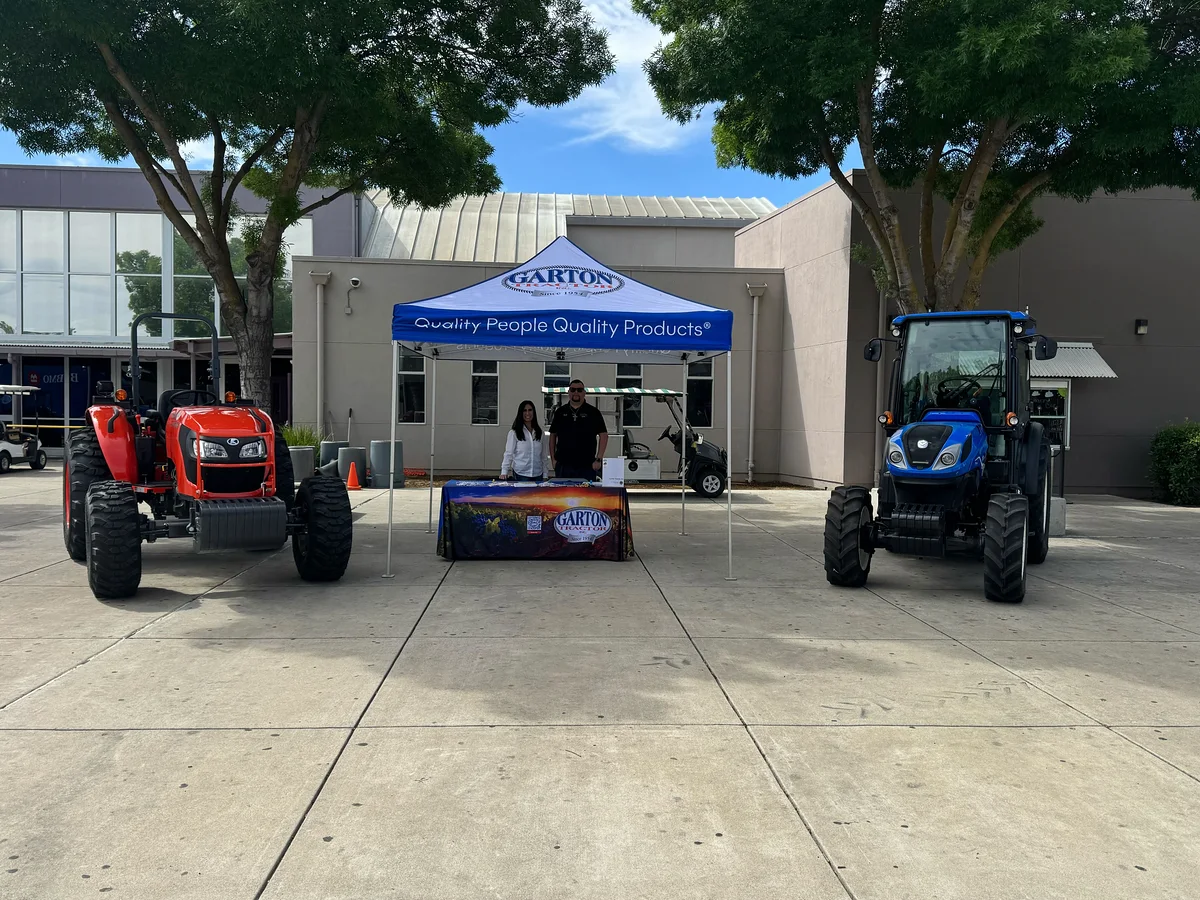 Two Garton Tractor representatives at an outdoor career-day display between red and blue tractors