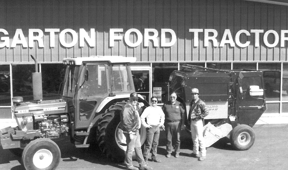 Garton family with customer Jameson buying a Ford tractor and a New Holland round baler outside the Garton Ford Tractor store